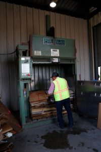 Man standing at a corrugated cardboard bailer.