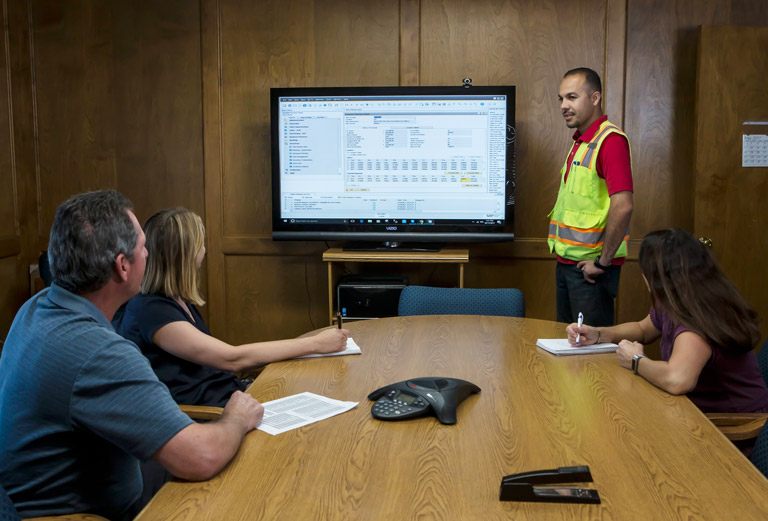 People reviewing forecasting data on computer monitor.