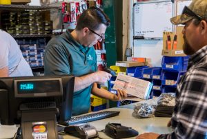 Employee at cash register scanning product.